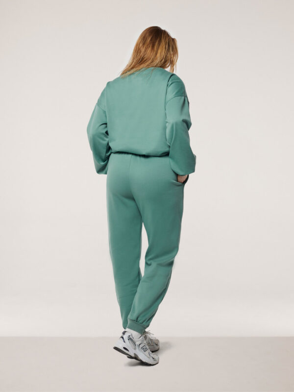 blonde woman wearing green jogging set size L back side